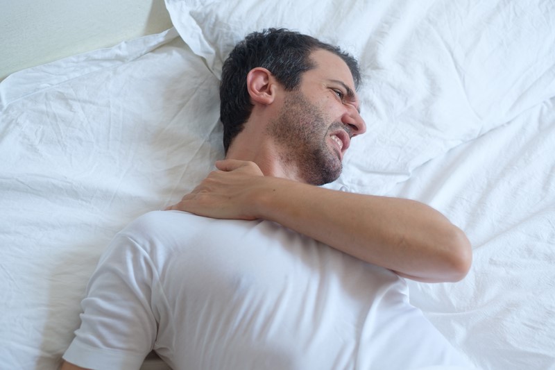 Man waking up in the morning and suffering because of backache