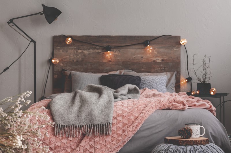 oak wood headboard with pastel bed, black lamp and lights